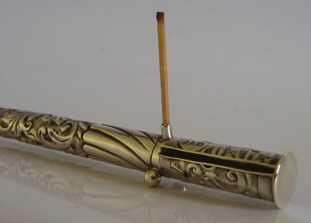 An elongated cylindrical silver Victorian wax holder featuring scrollwork engraving and a camel figure at the terminal. View XI