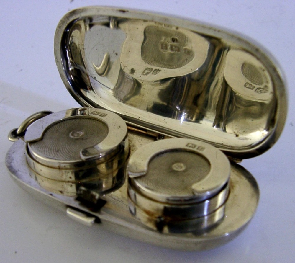 An open Edwardian sterling silver double sovereign case with gold hinge detail showing two spring-loaded coin compartments.