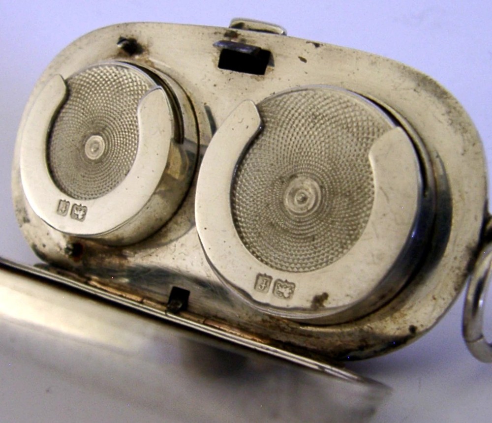 An open Edwardian sterling silver double sovereign case with gold hinge detail showing two spring-loaded coin compartments. View II
