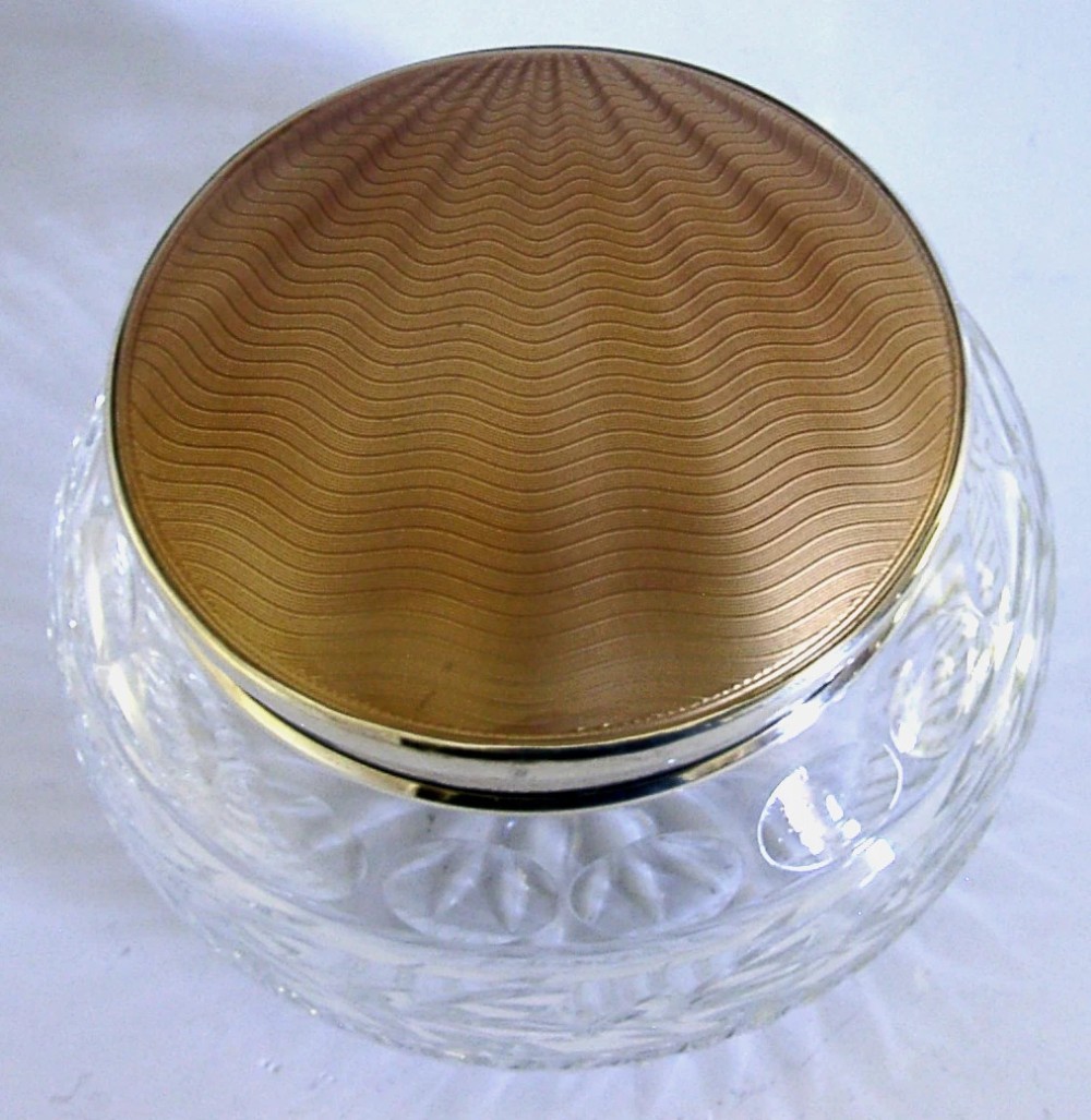 A circular cut glass vanity jar with a sterling silver rim and a bronze guilloche enamelled lid displaying a sunburst pattern. View II