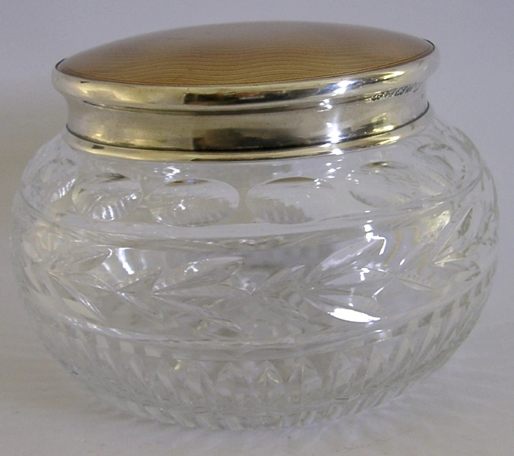 A circular cut glass vanity jar with a sterling silver rim and a bronze guilloche enamelled lid displaying a sunburst pattern. View III