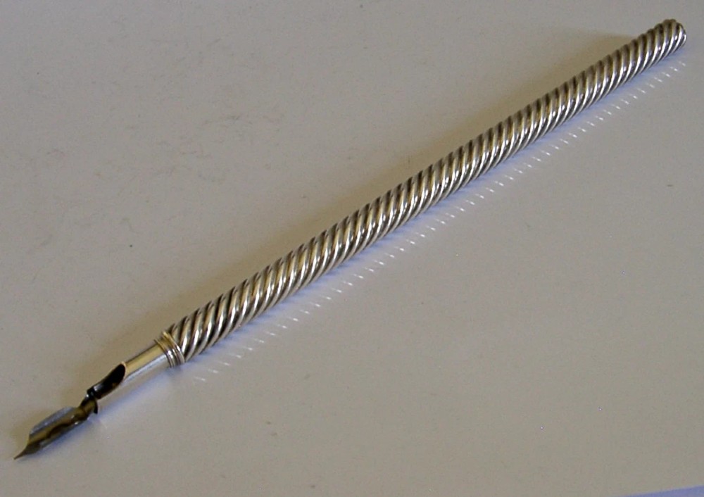 A Victorian sterling silver dip pen featuring a spiral fluted barrel and a metal writing nib.