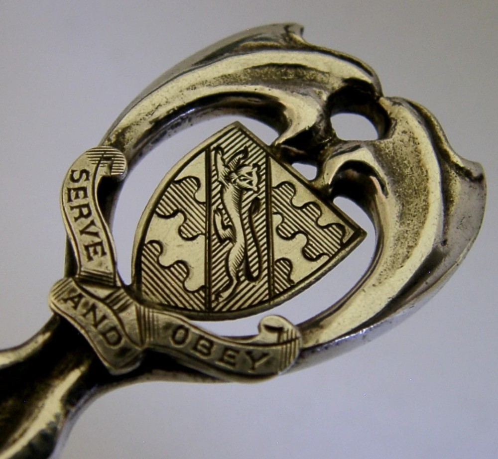 An Art Deco sterling silver spoon featuring an openwork coat of arms handle terminal, a geometric stem, and a polished teardrop bowl. View II