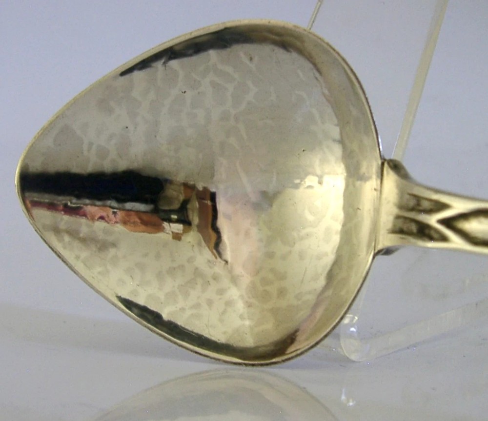 An Art Deco sterling silver spoon featuring an openwork coat of arms handle terminal, a geometric stem, and a polished teardrop bowl. View III