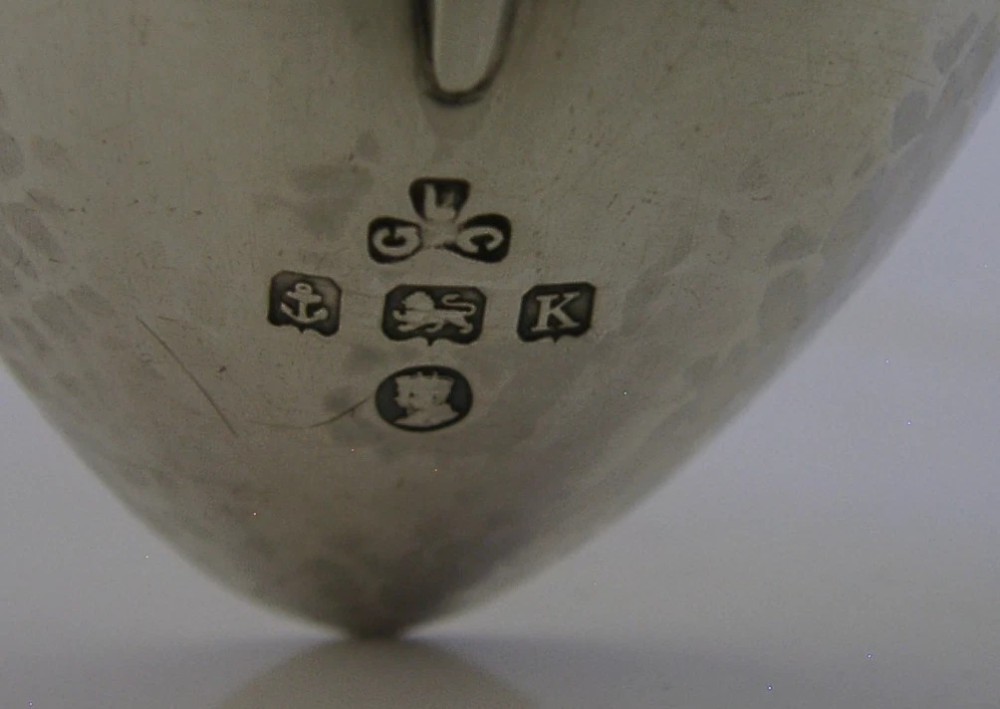 An Art Deco sterling silver spoon featuring an openwork coat of arms handle terminal, a geometric stem, and a polished teardrop bowl. View VIII