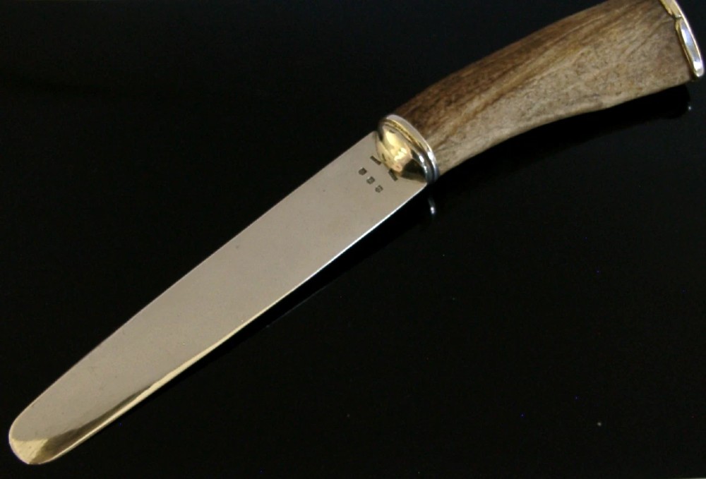 A Scottish provincial sterling silver page turner featuring a smooth silver blade mounted to a natural curved horn handle with a silver end cap. View II