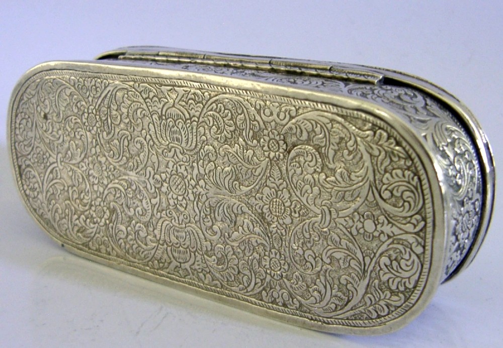 An oval antique solid silver box decorated with elaborate hand-chased floral repousse scrollwork. View III