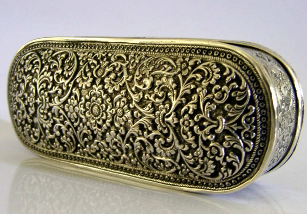 An oval antique solid silver box decorated with elaborate hand-chased floral repousse scrollwork. View IV