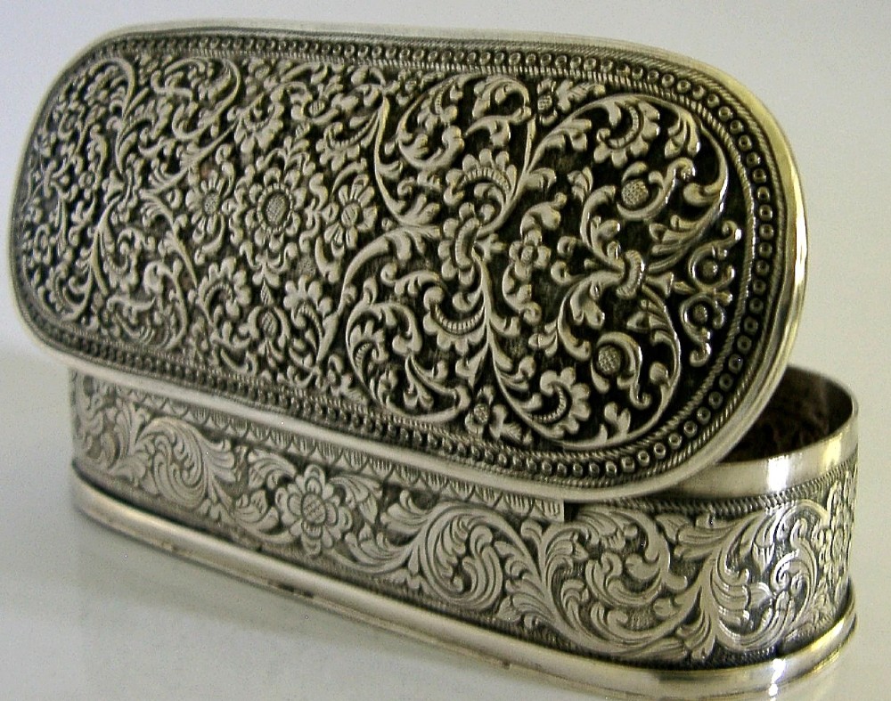 An oval antique solid silver box decorated with elaborate hand-chased floral repousse scrollwork. View VI