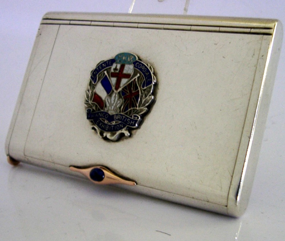 A rectangular silver cigarette case featuring a central enamel emblem depicting British and French flags with Entente Cordiale lettering and a gold thumbpiece. View V
