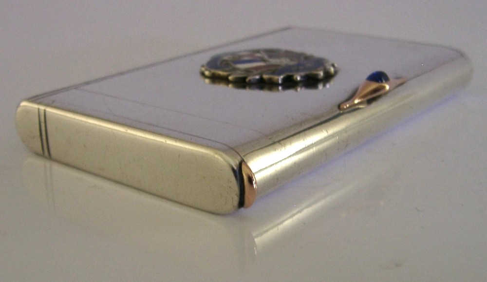 A rectangular silver cigarette case featuring a central enamel emblem depicting British and French flags with Entente Cordiale lettering and a gold thumbpiece. View VII