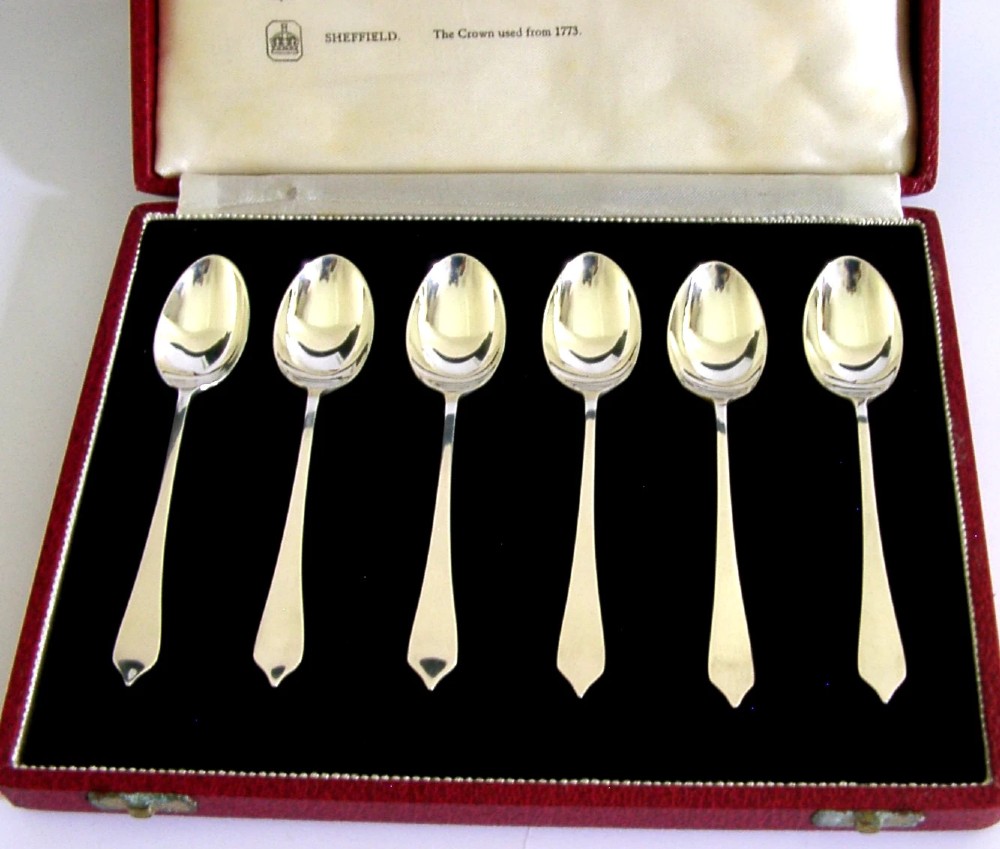 A set of six sterling silver teaspoons presented inside a fitted red velvet presentation box.