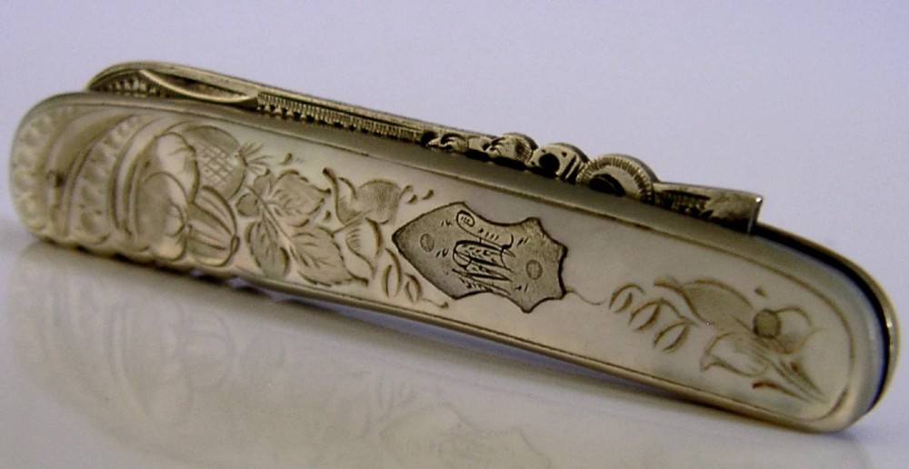 An Edwardian folding fruit knife with a carved mother-of-pearl handle and engraved silver shield cartouche.