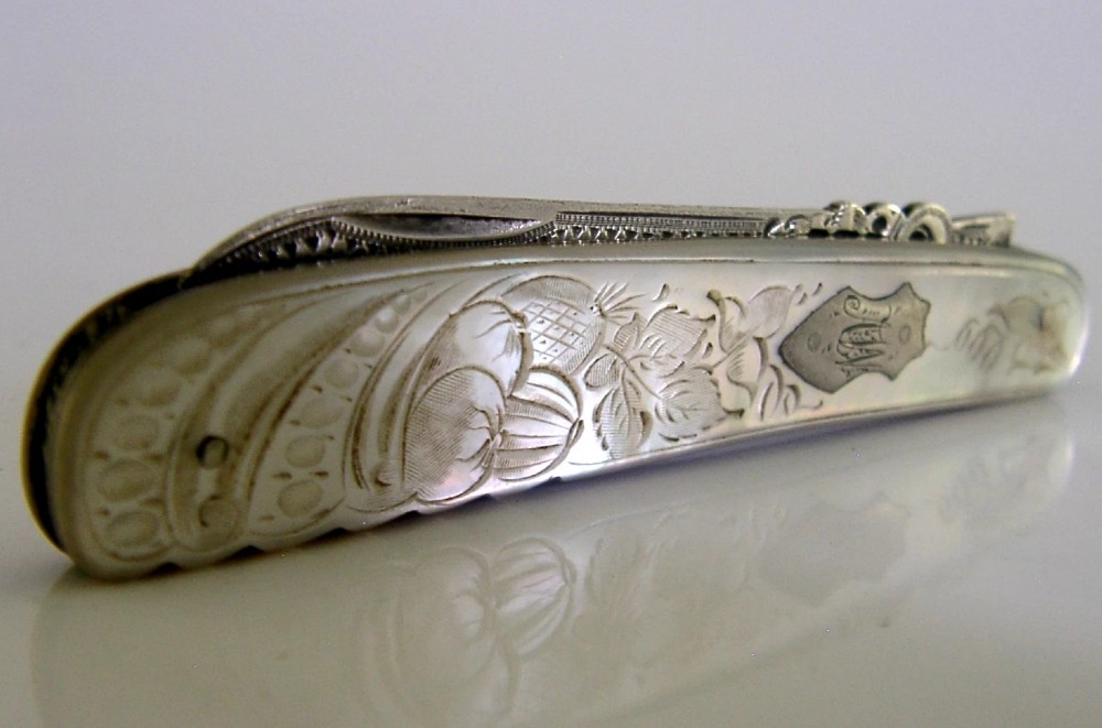 An Edwardian folding fruit knife with a carved mother-of-pearl handle and engraved silver shield cartouche. View VI