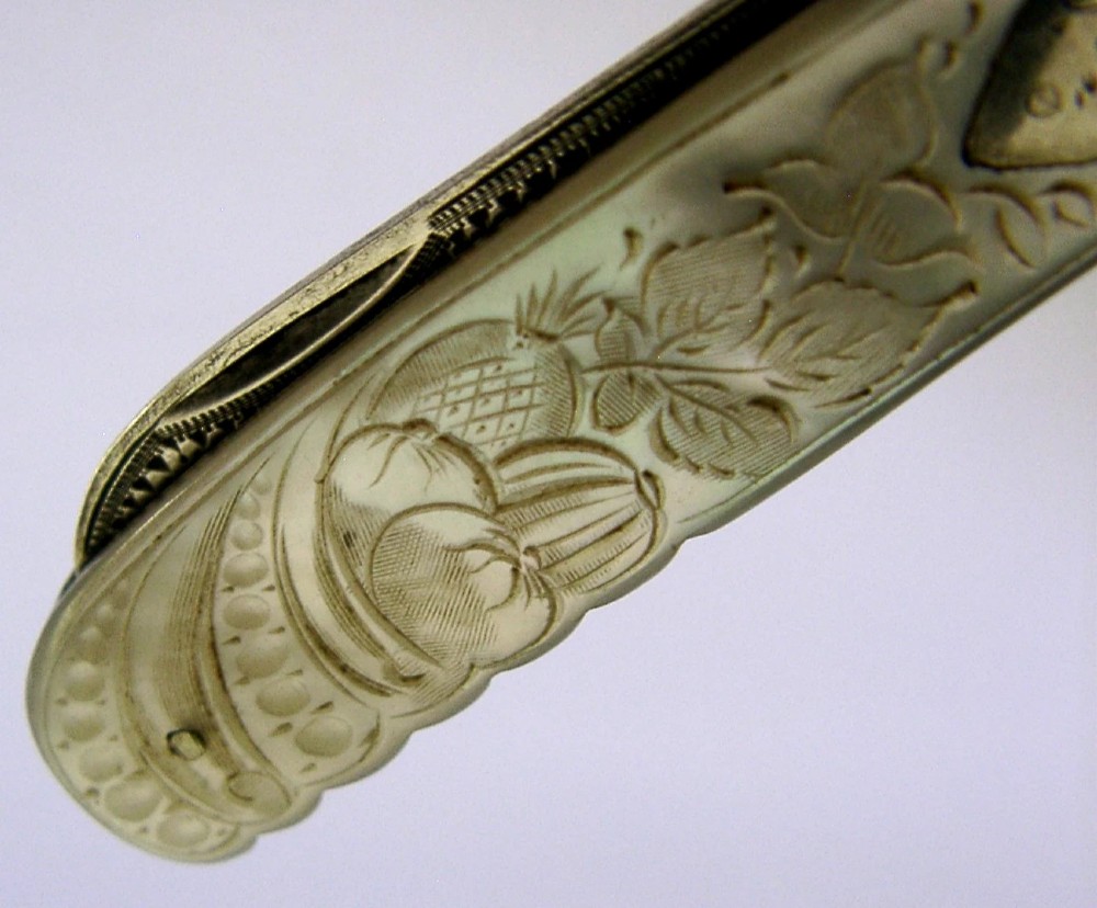 An Edwardian folding fruit knife with a carved mother-of-pearl handle and engraved silver shield cartouche. View VII