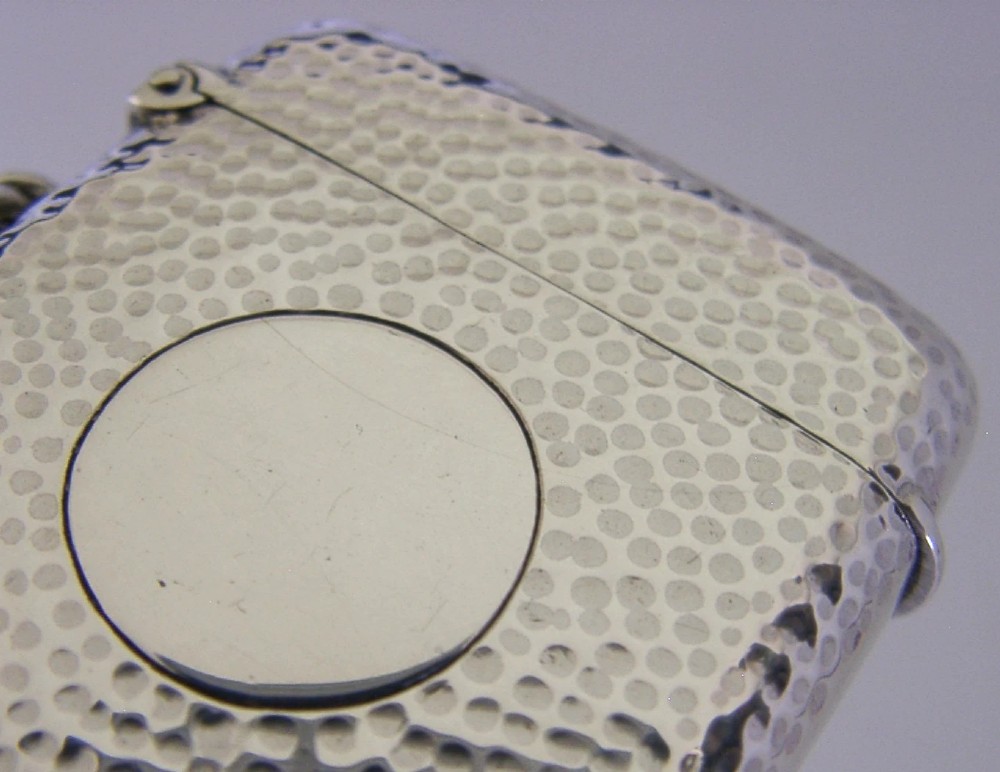 An Edwardian sterling silver pocket vesta case featuring a planished hammered surface and a central unengraved circular cartouche. View II