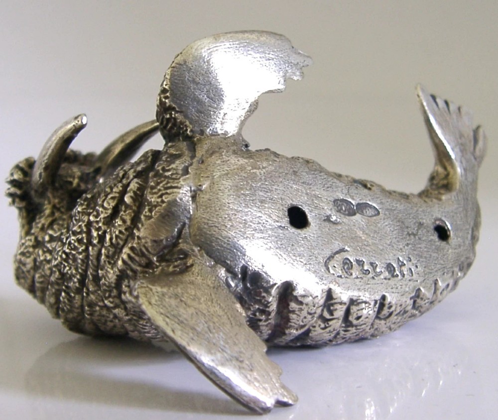 A detailed cast silver walrus figurine shown in profile with long downward tusks and textured skin. View VIII
