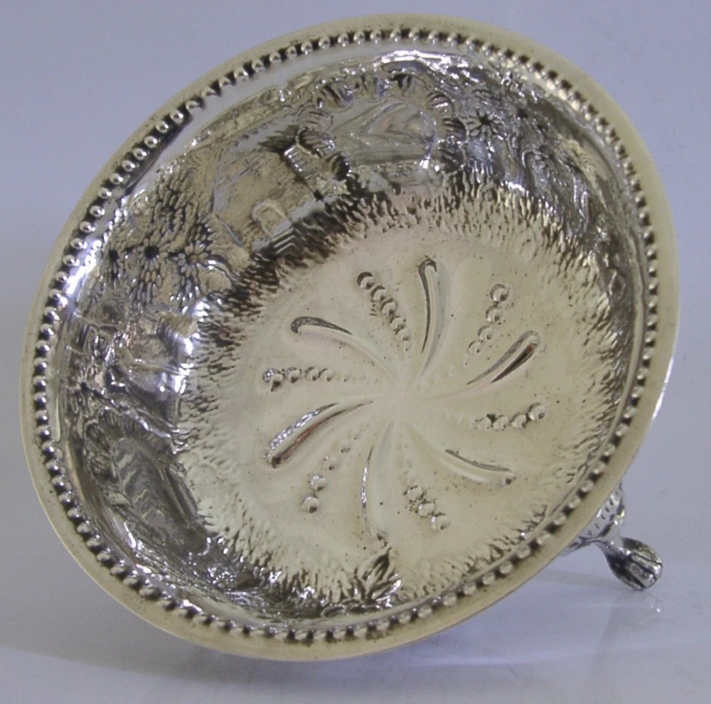 A late Victorian sterling silver bowl decorated with chased pastoral scenes and supported by three lion-mask legs. View III