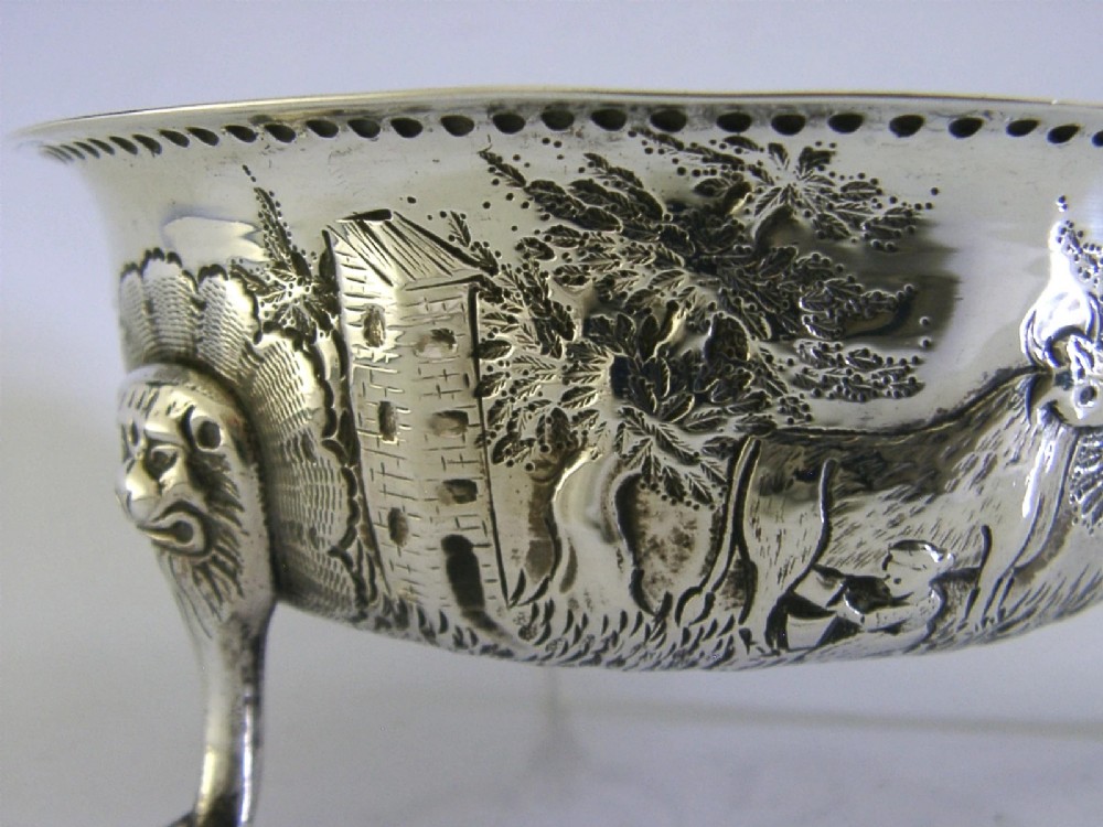 A late Victorian sterling silver bowl decorated with chased pastoral scenes and supported by three lion-mask legs. View VI