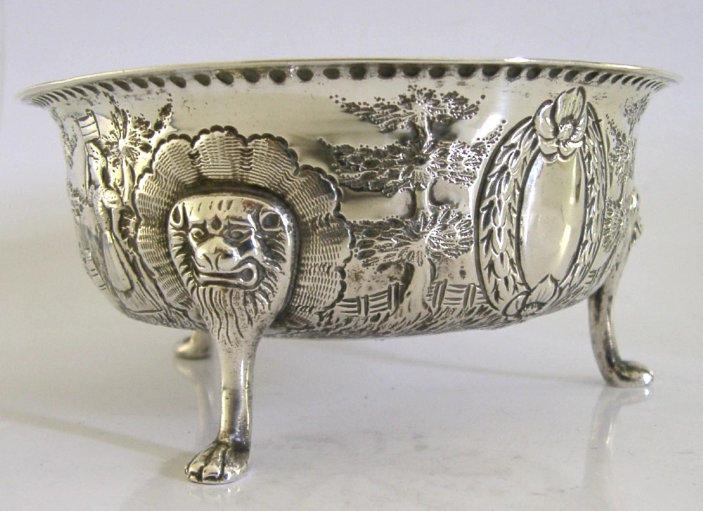 A late Victorian sterling silver bowl decorated with chased pastoral scenes and supported by three lion-mask legs. View VII