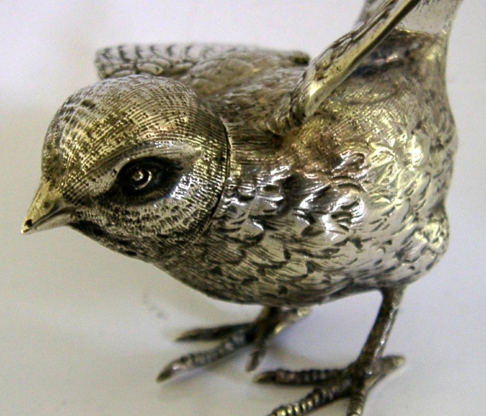 A solid silver pepper pot finely chased in the detailed form of a bird chick with outstretched wings. View III