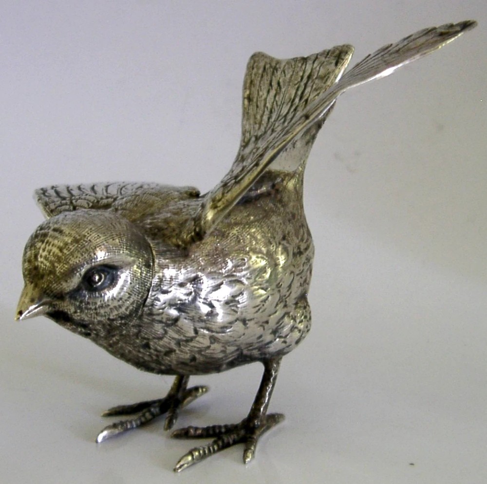 A solid silver pepper pot finely chased in the detailed form of a bird chick with outstretched wings. View IV
