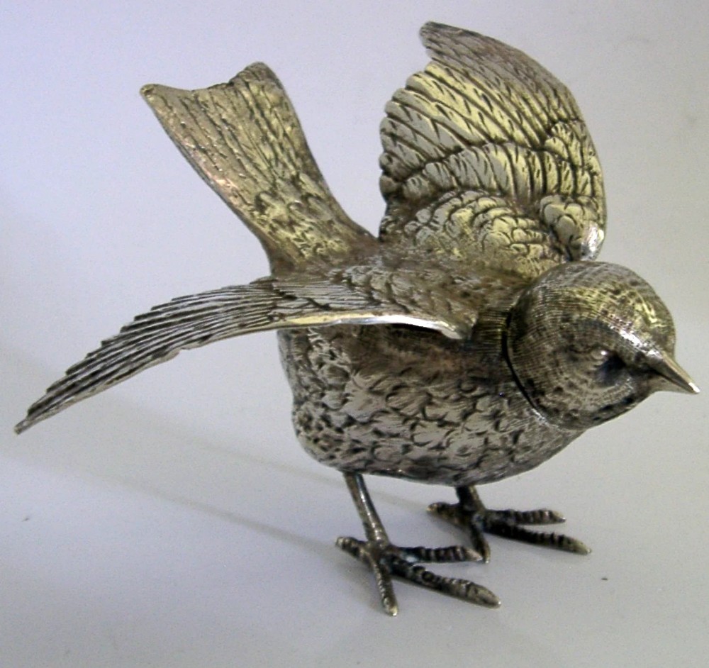 A solid silver pepper pot finely chased in the detailed form of a bird chick with outstretched wings. View V