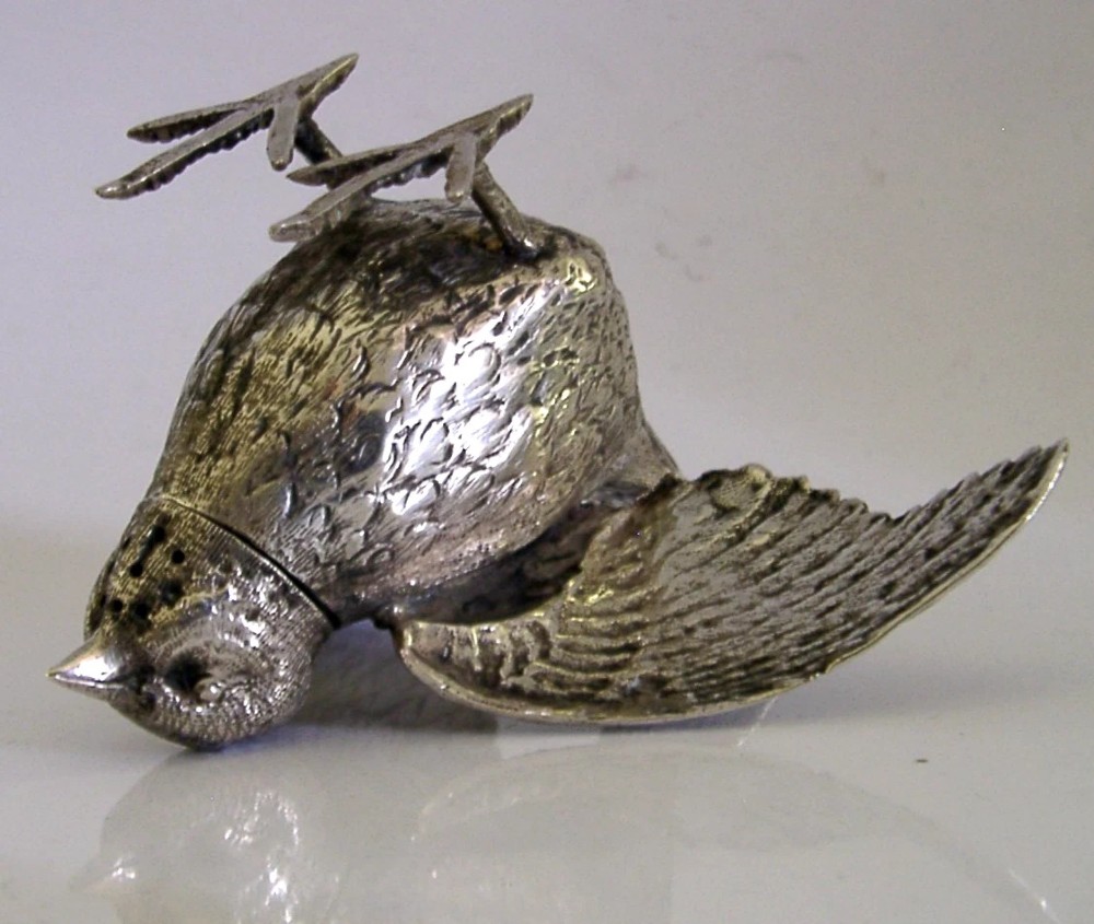 A solid silver pepper pot finely chased in the detailed form of a bird chick with outstretched wings. View IX