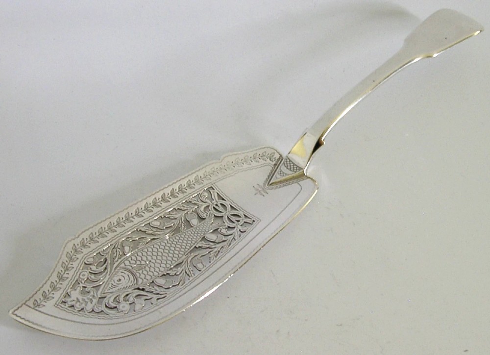 A George IV sterling silver fish slice featuring a hand-pierced central fish motif with leaf engraving and a contoured handle.