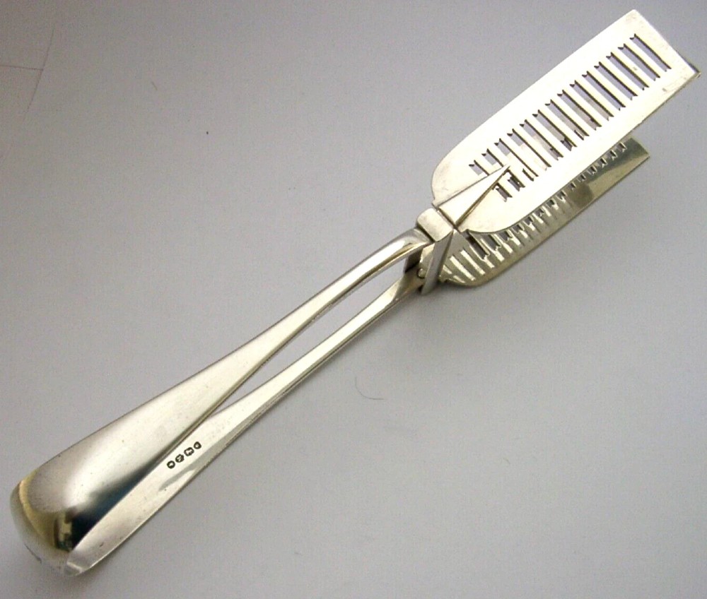 Victorian sterling silver serving tongs featuring slotted rectangular blades and a spring-hinged handle stamped with hallmarks. View IV