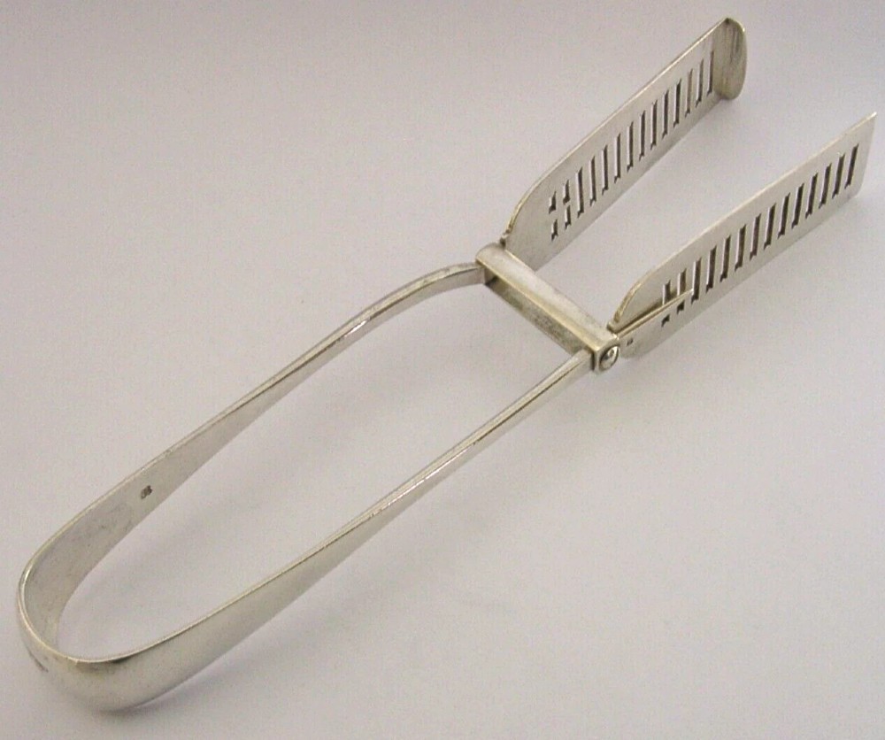Victorian sterling silver serving tongs featuring slotted rectangular blades and a spring-hinged handle stamped with hallmarks. View VI