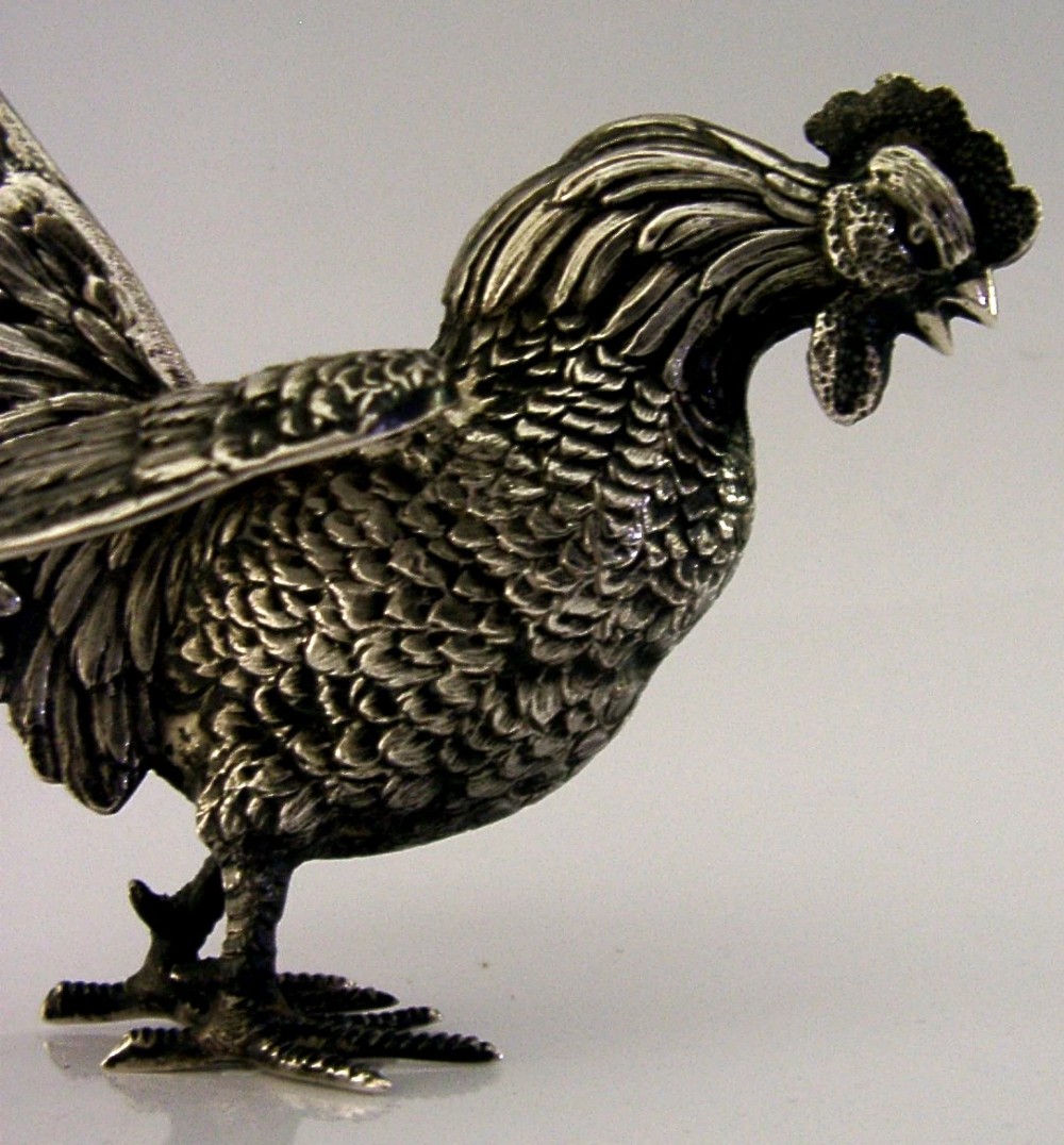 A solid silver figurine of a cockerel standing with open tail feathers and detailed feather chasing. View VI