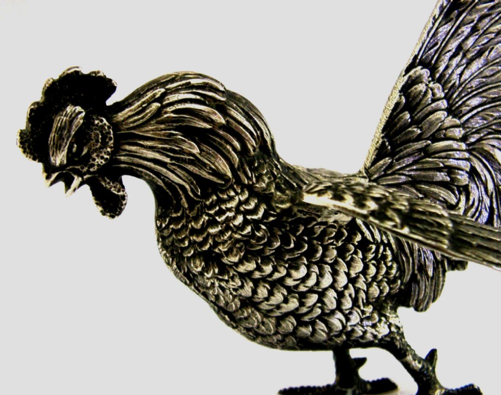 A solid silver figurine of a cockerel standing with open tail feathers and detailed feather chasing. View VII