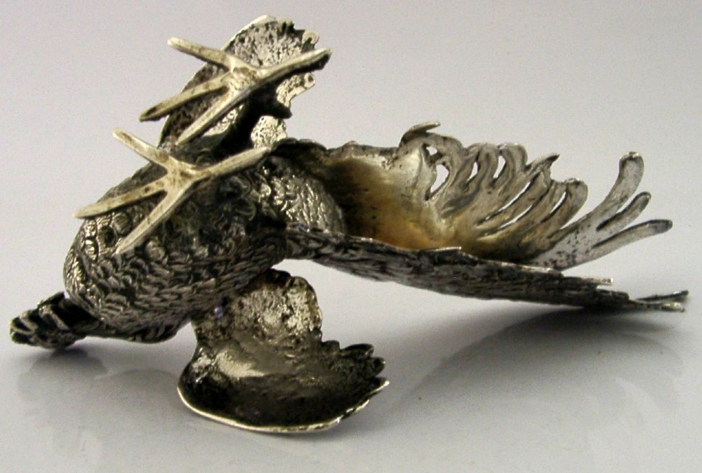 A solid silver figurine of a cockerel standing with open tail feathers and detailed feather chasing. View VIII