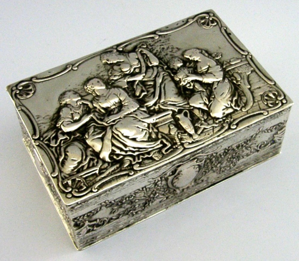 A rectangular silver box featuring embossed classical figures on the hinged lid and foliate scrollwork along the sides. View VIII