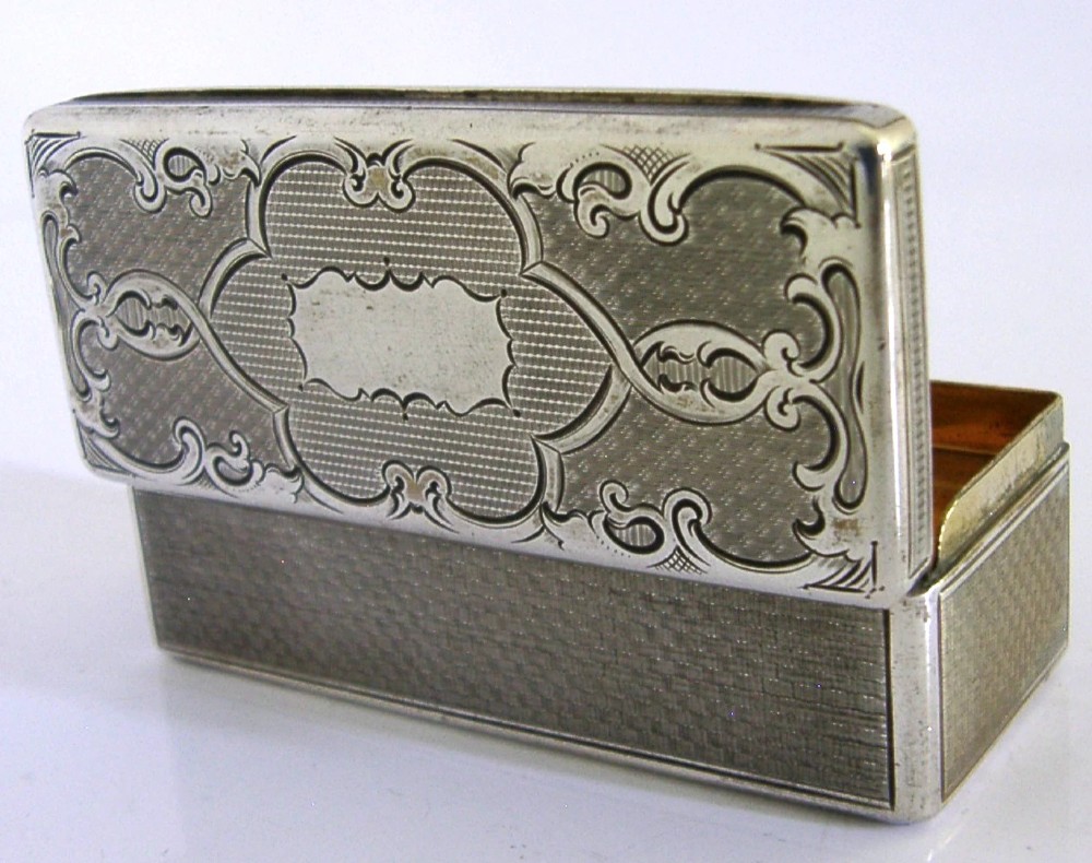 An antique rectangular Austro-Hungarian solid silver box featuring intricate engraved scrollwork and an open hinged lid displaying a gilt interior.