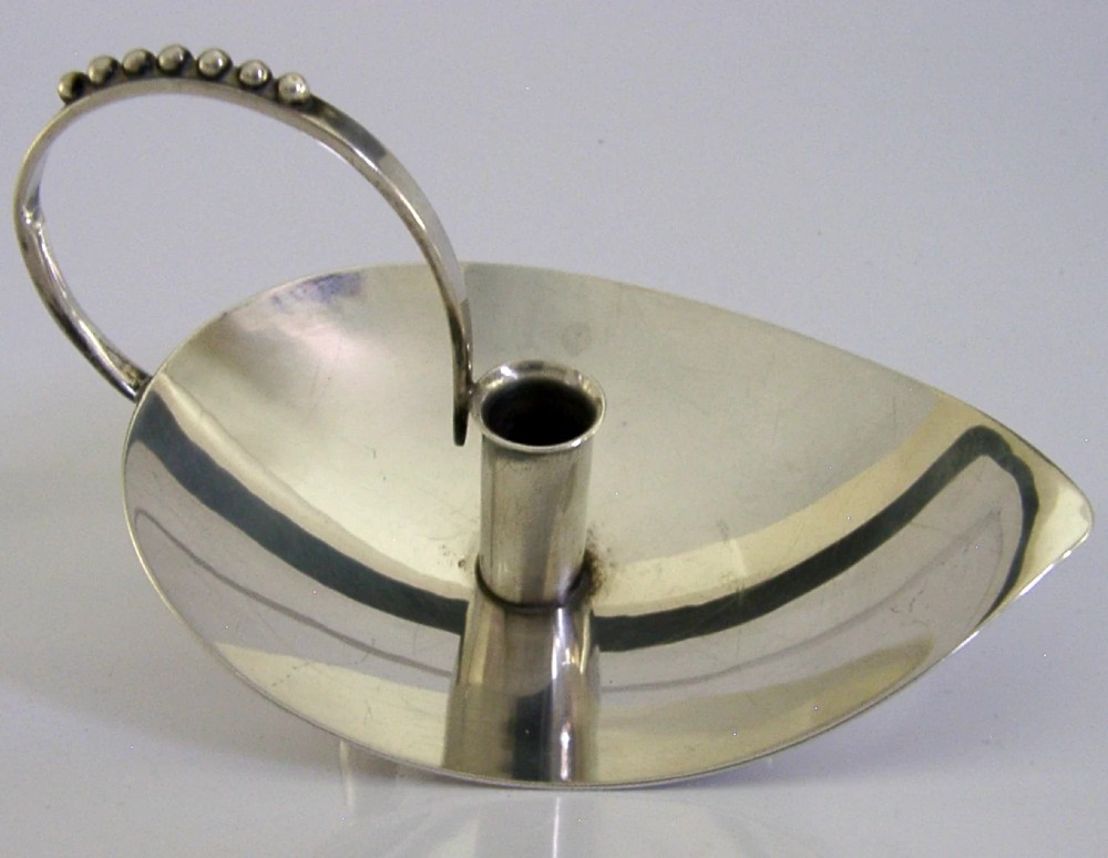 A sterling silver leaf-shaped chamberstick featuring a central candle socket and a looped handle accented with small silver spheres.