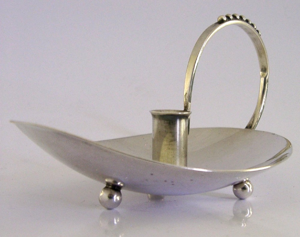A sterling silver leaf-shaped chamberstick featuring a central candle socket and a looped handle accented with small silver spheres. View IV