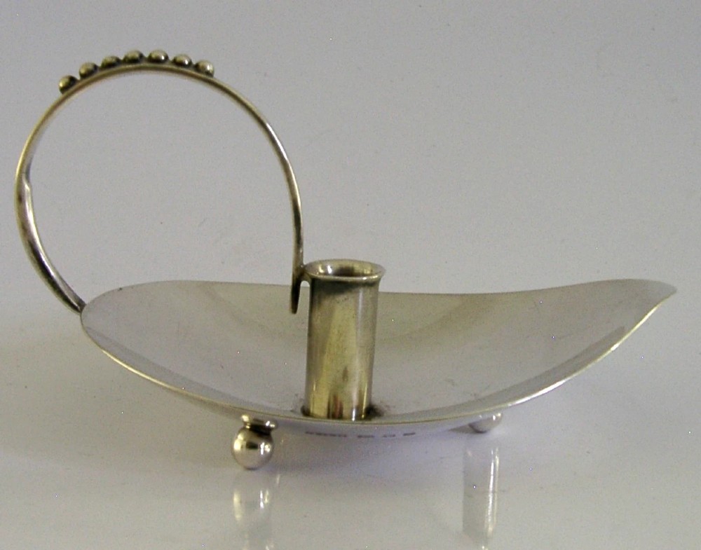 A sterling silver leaf-shaped chamberstick featuring a central candle socket and a looped handle accented with small silver spheres. View V