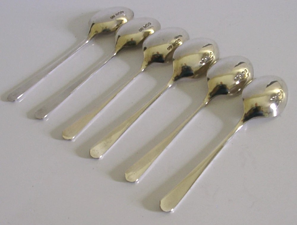 A set of six Art Deco sterling silver teaspoons arranged neatly inside a dark blue velvet-lined presentation case. View VII