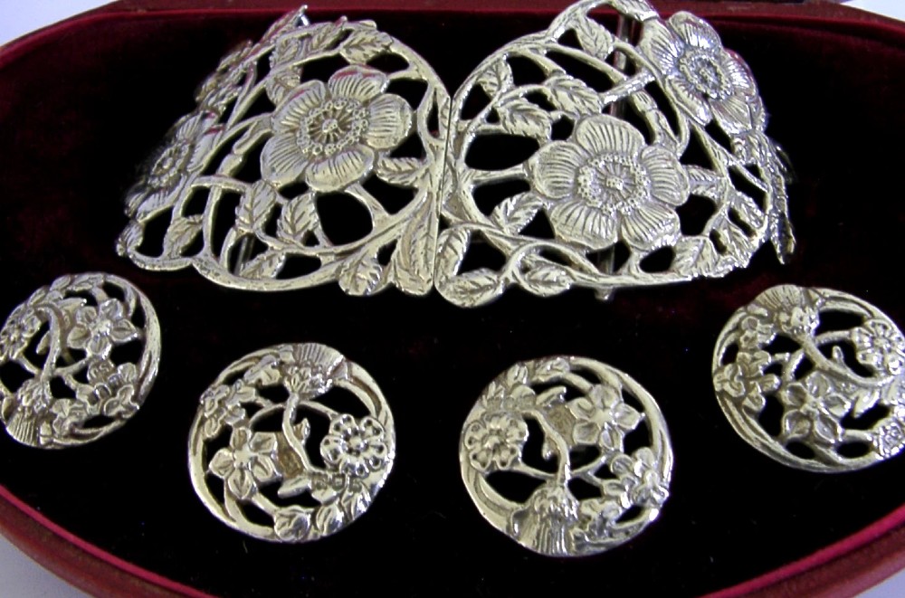 An Edwardian sterling silver belt buckle and four matching round buttons with pierced English rose motifs, presented inside a crimson velvet-lined oval case. View IV