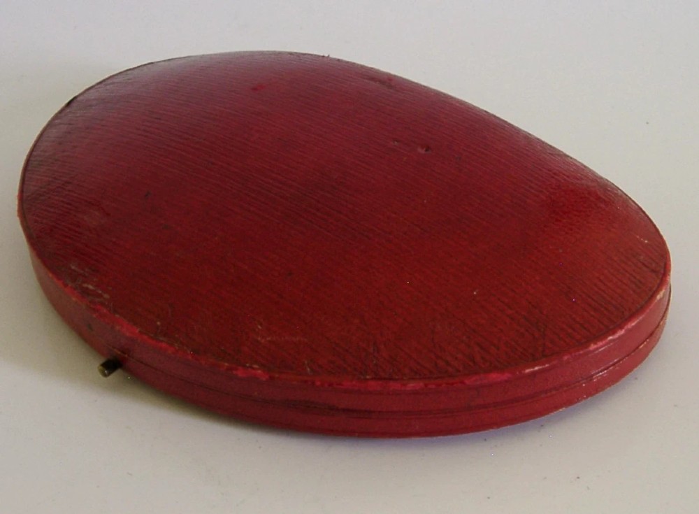 An Edwardian sterling silver belt buckle and four matching round buttons with pierced English rose motifs, presented inside a crimson velvet-lined oval case. View VII