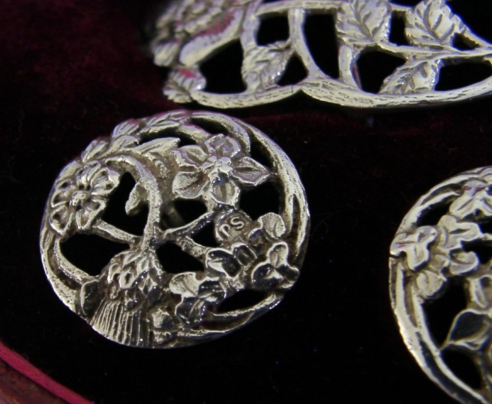 An Edwardian sterling silver belt buckle and four matching round buttons with pierced English rose motifs, presented inside a crimson velvet-lined oval case. View VIII