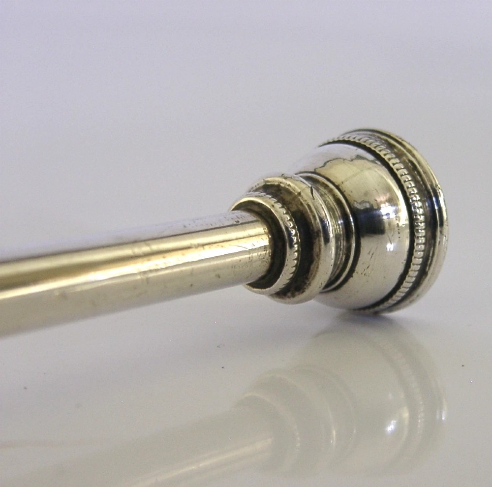 An Edwardian sterling silver hunting horn with ribbed body accents and a flared bell resting on a pale surface. View II