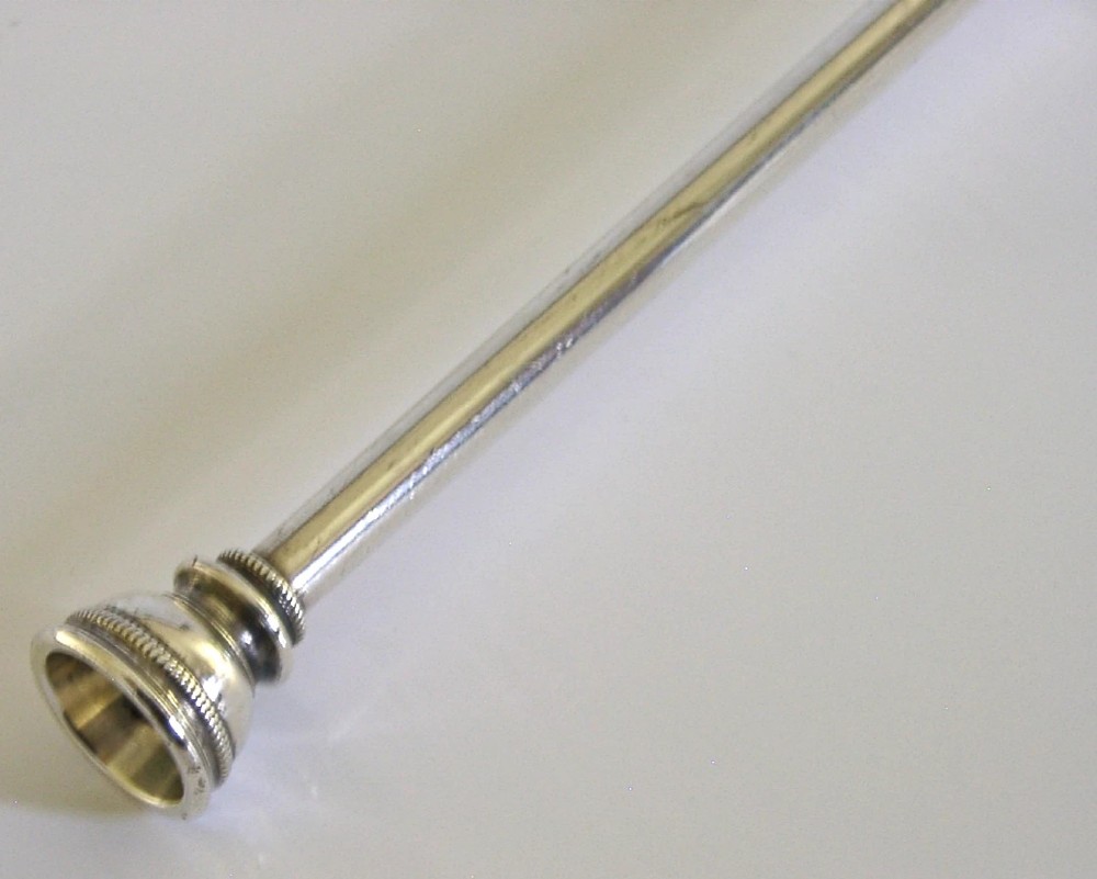 An Edwardian sterling silver hunting horn with ribbed body accents and a flared bell resting on a pale surface. View IV