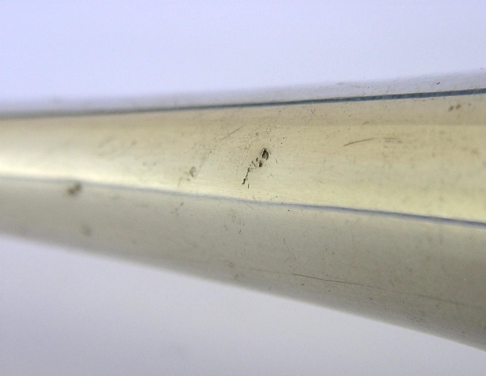 An Edwardian sterling silver hunting horn with ribbed body accents and a flared bell resting on a pale surface. View VII