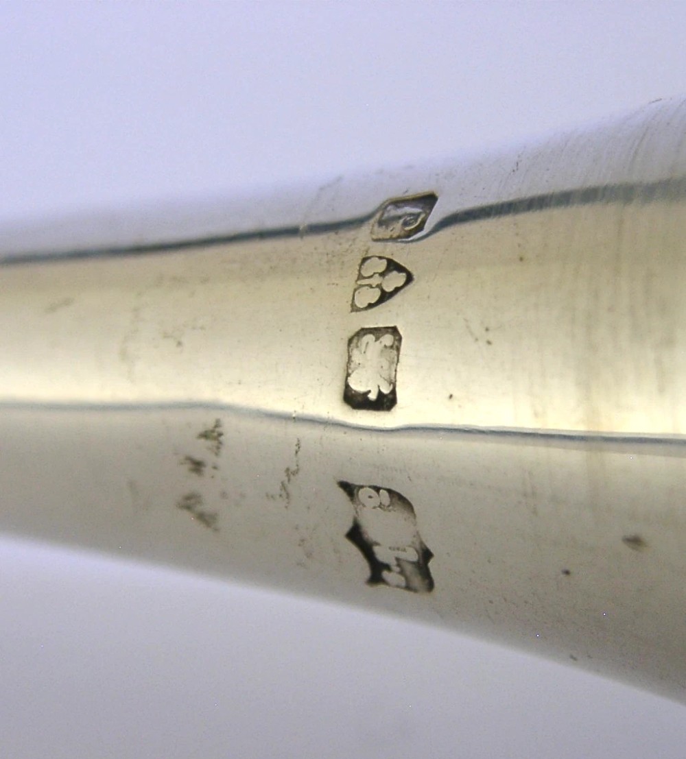 An Edwardian sterling silver hunting horn with ribbed body accents and a flared bell resting on a pale surface. View VIII