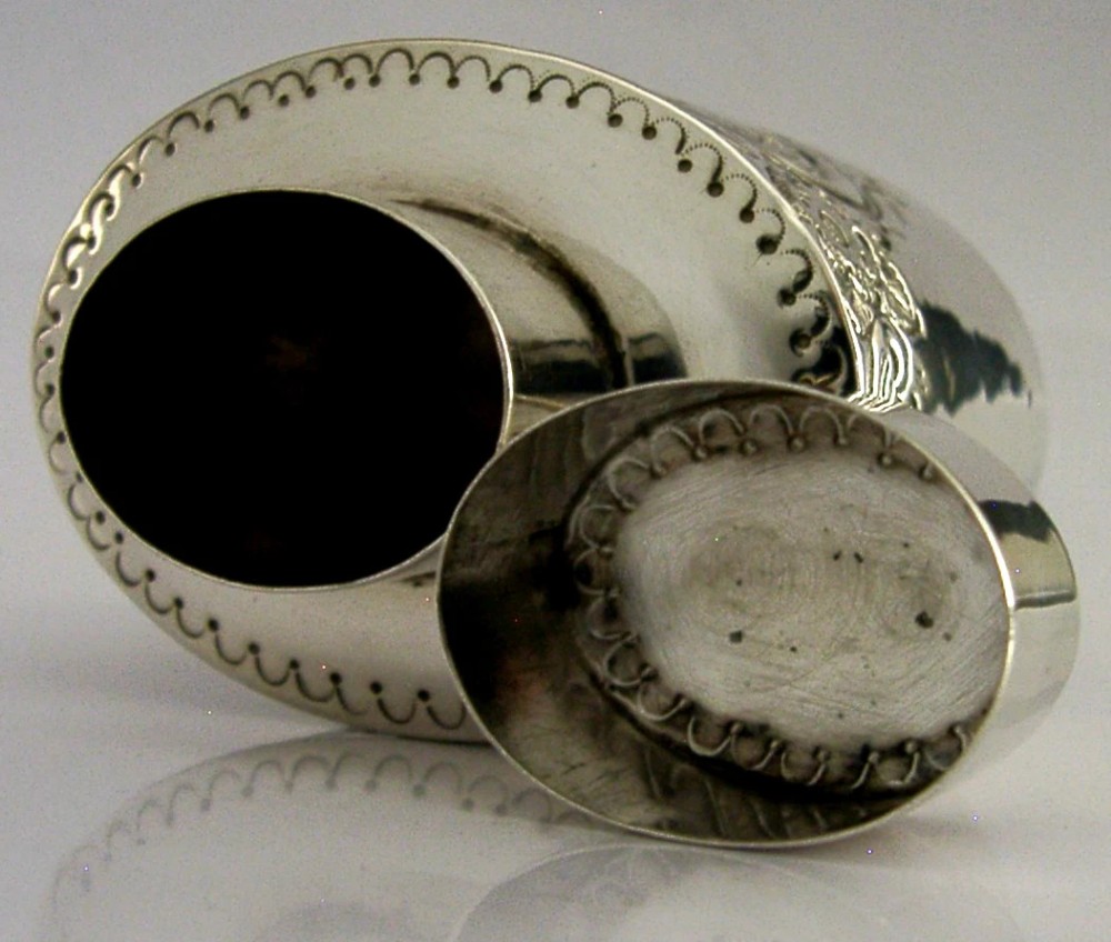 A cylindrical Victorian sterling silver tea caddy featuring chased floral and scroll motifs with a fitted cylindrical lid displaying hallmarks. View VI