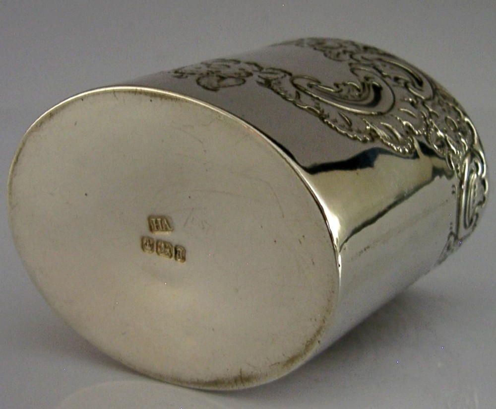 A cylindrical Victorian sterling silver tea caddy featuring chased floral and scroll motifs with a fitted cylindrical lid displaying hallmarks. View VIII