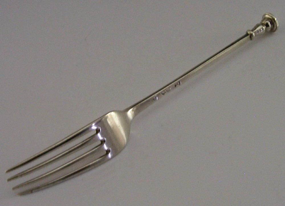 A Victorian sterling silver seal top fork featuring four tines and hallmarks along the slender stem.